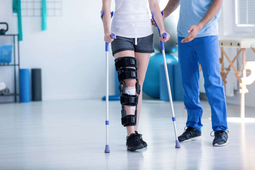 patient walking on crutches with knee brace