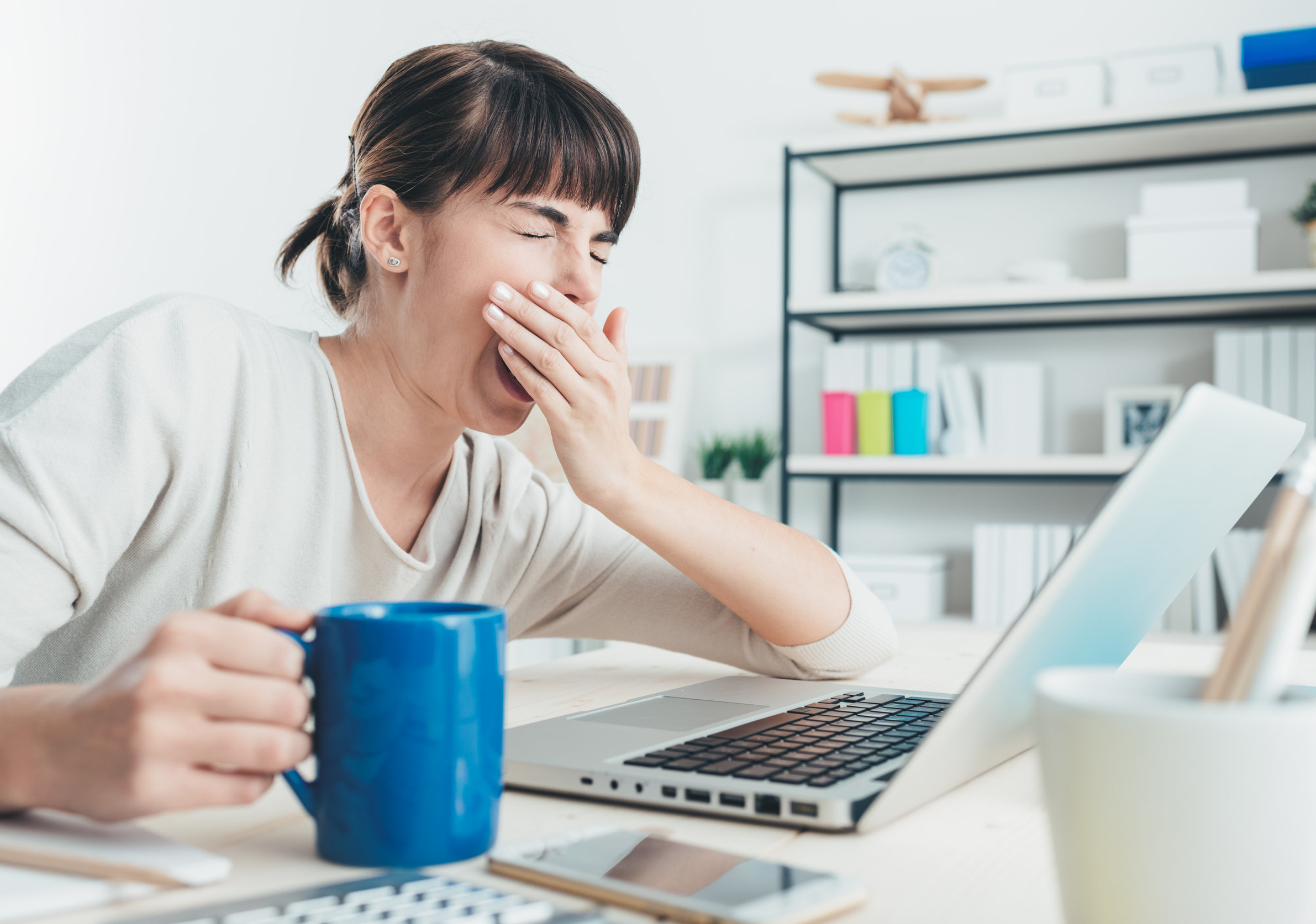 Woman yawning while trying to work