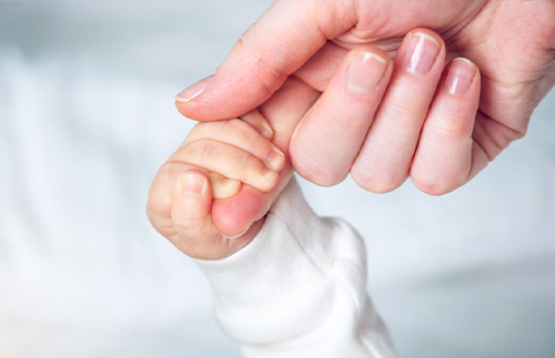 baby hand holding an adult hand