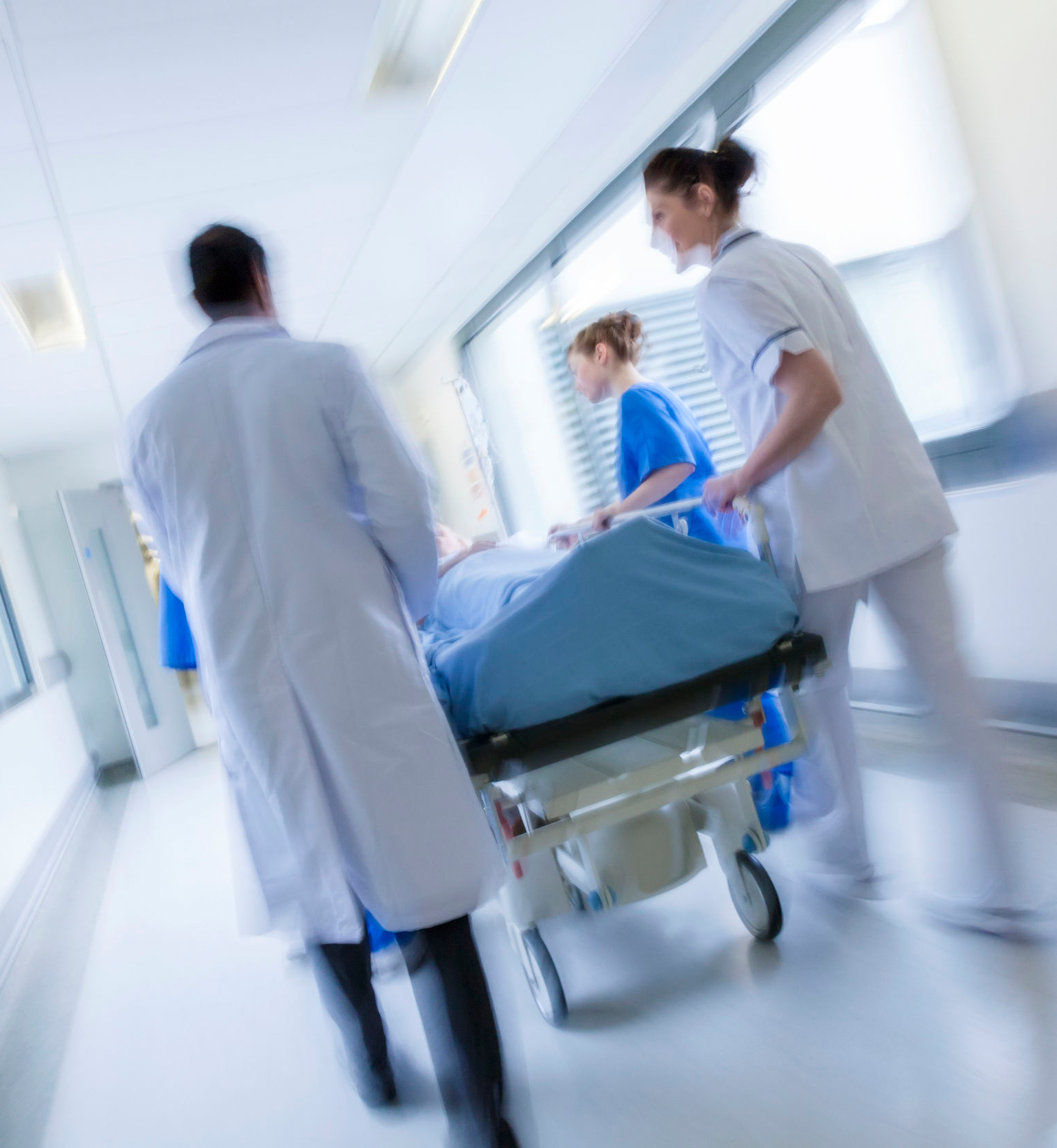 doctors and nurses wheeling a patient down the hallway